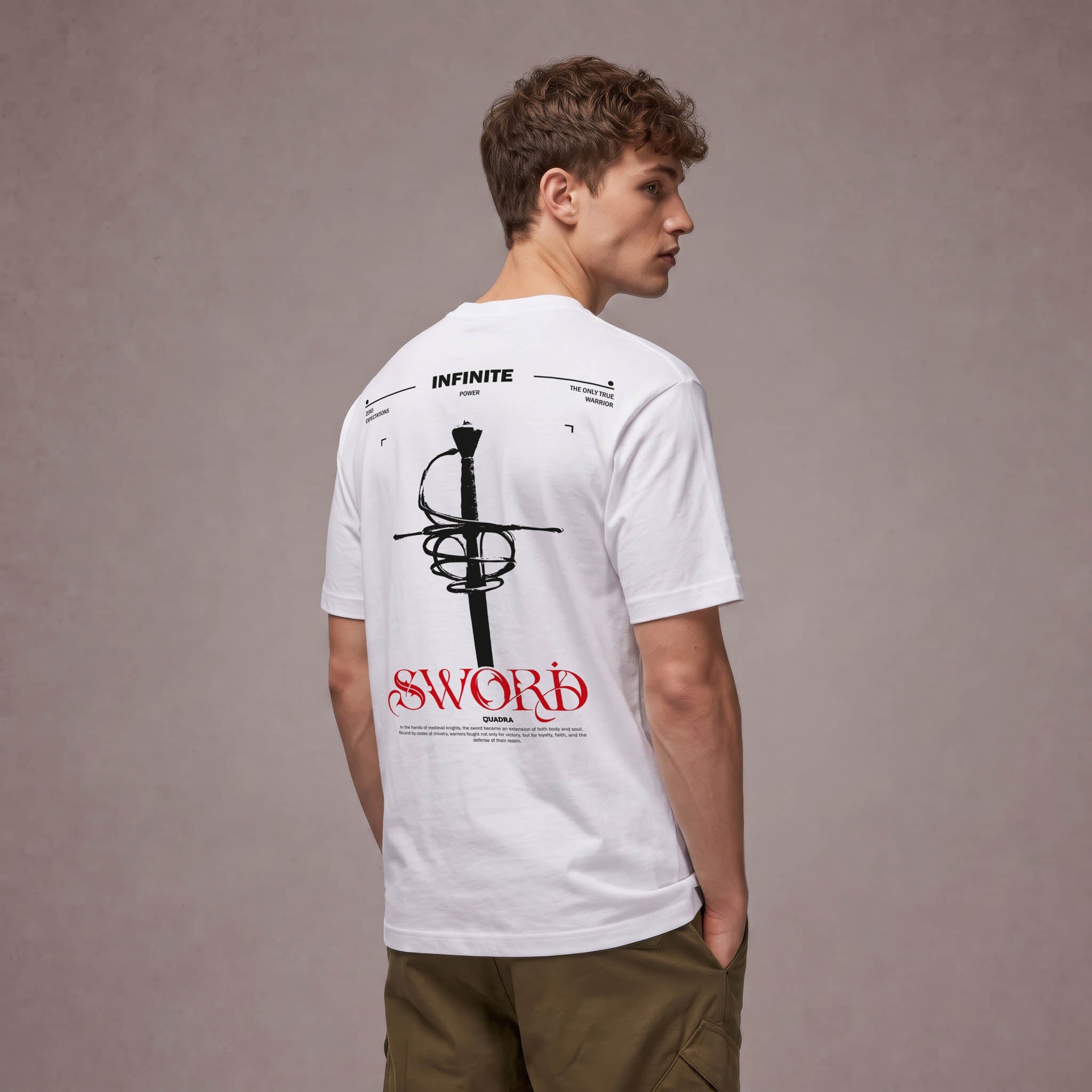 Hombre de espaldas con camiseta blanca Infinite Sword de QUADRA GALLERY, estampada con una espada negra y tipografía roja.