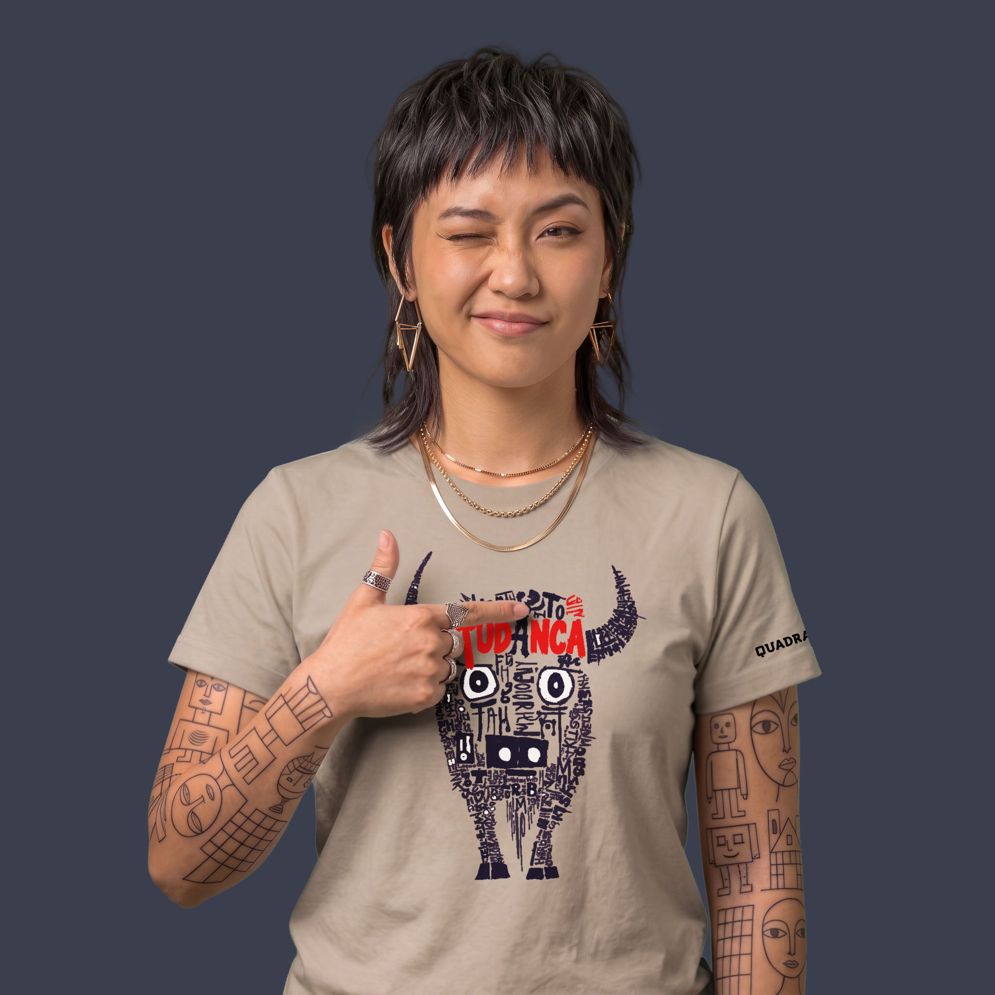 Camiseta unisex de algodón orgánico color tierra claro con diseño gráfico de una vaca tudanca formada por palabras y letras en negro y rojo, con la marca QUADRA impresa en la manga